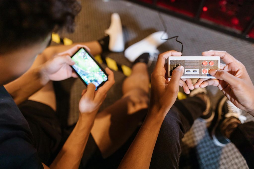 Close-up of teenagers playing mobile and retro video games indoors, showcasing fun and technology.